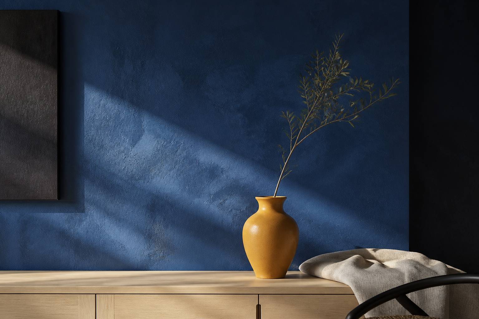 Mur bleu cobalto avec un vase en céramique ocra sur une console en bois